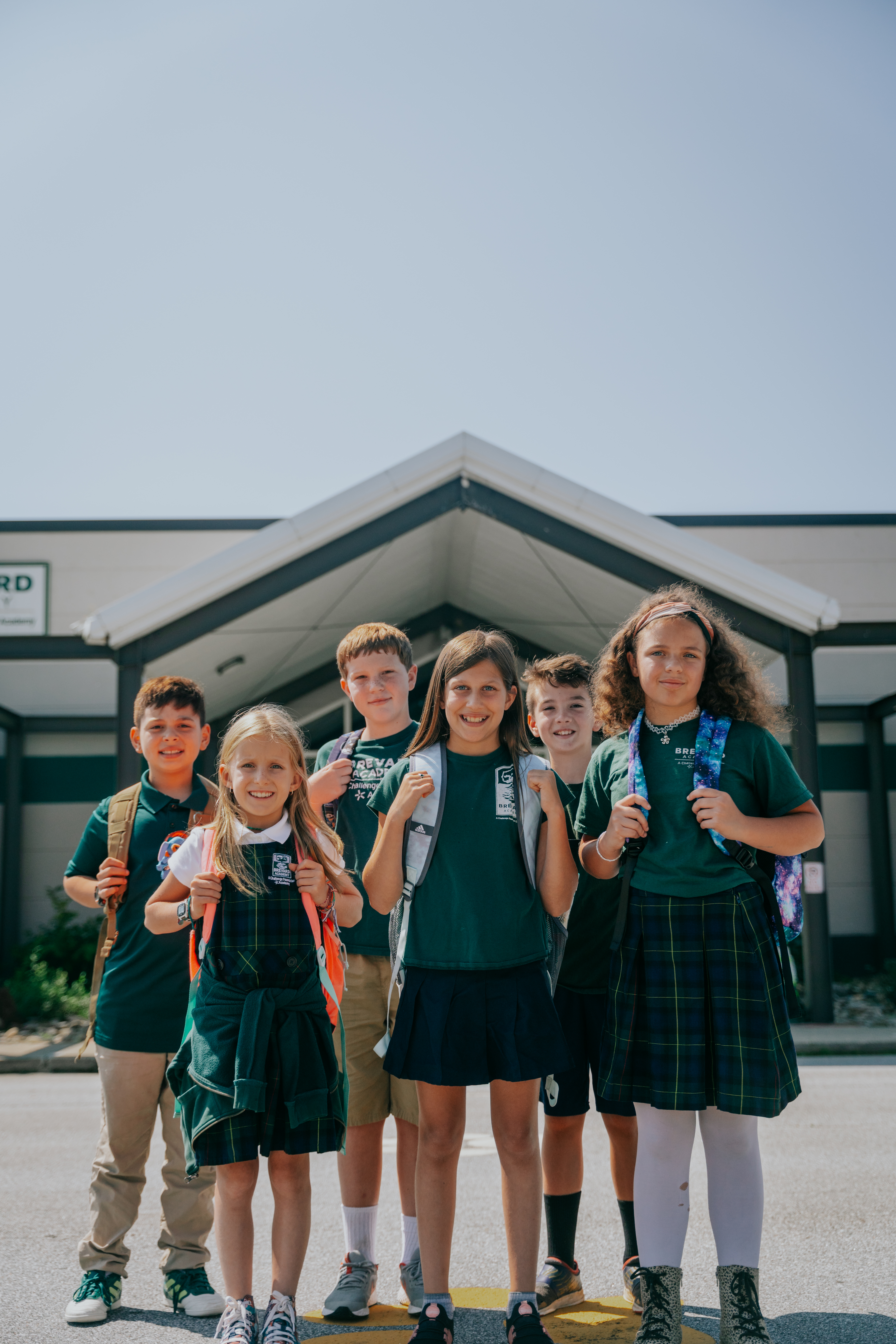 Group of students smiling in front of school